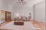 Experience modern living in this spacious living room featuring a vaulted ceiling with a stylish fan and a large sliding glass door that opens to a serene outdoor space.