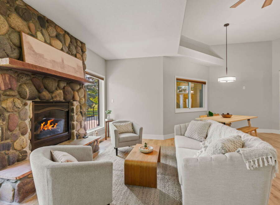 Cozy living room featuring a striking floor-to-ceiling stone fireplace with a rustic wooden mantel.