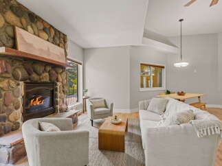 Cozy living room featuring a striking floor-to-ceiling stone fireplace with a rustic wooden mantel.