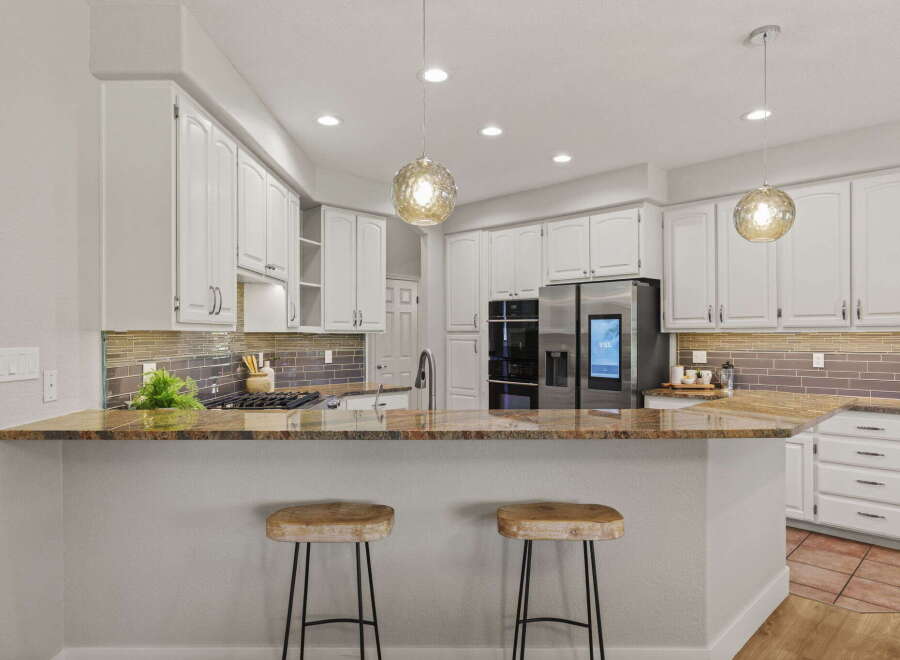This modern kitchen boasts sleek white cabinetry and a stunning granite countertop, perfect for entertaining.