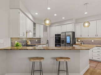 This modern kitchen boasts sleek white cabinetry and a stunning granite countertop, perfect for entertaining.