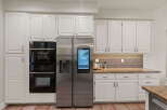 This modern kitchen features a sleek stainless steel side-by-side refrigerator with a built-in touchscreen display, perfect for managing your smart home.