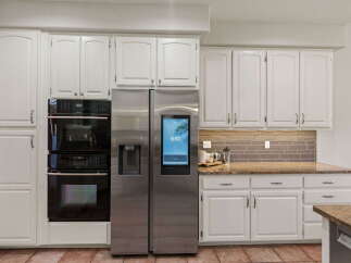 This modern kitchen features a sleek stainless steel side-by-side refrigerator with a built-in touchscreen display, perfect for managing your smart home.