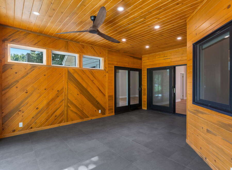 Step into this beautifully designed sunroom, featuring warm, wood-paneled walls and a slatted wood ceiling.
