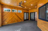 Step into this beautifully designed sunroom, featuring warm, wood-paneled walls and a slatted wood ceiling.