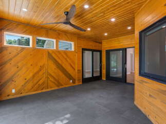 Step into this beautifully designed sunroom, featuring warm, wood-paneled walls and a slatted wood ceiling.
