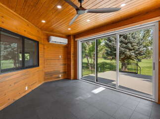 Enjoy the outdoors from this charming sunroom, featuring a modern ceiling fan and a convenient air conditioning unit for year-round comfort.