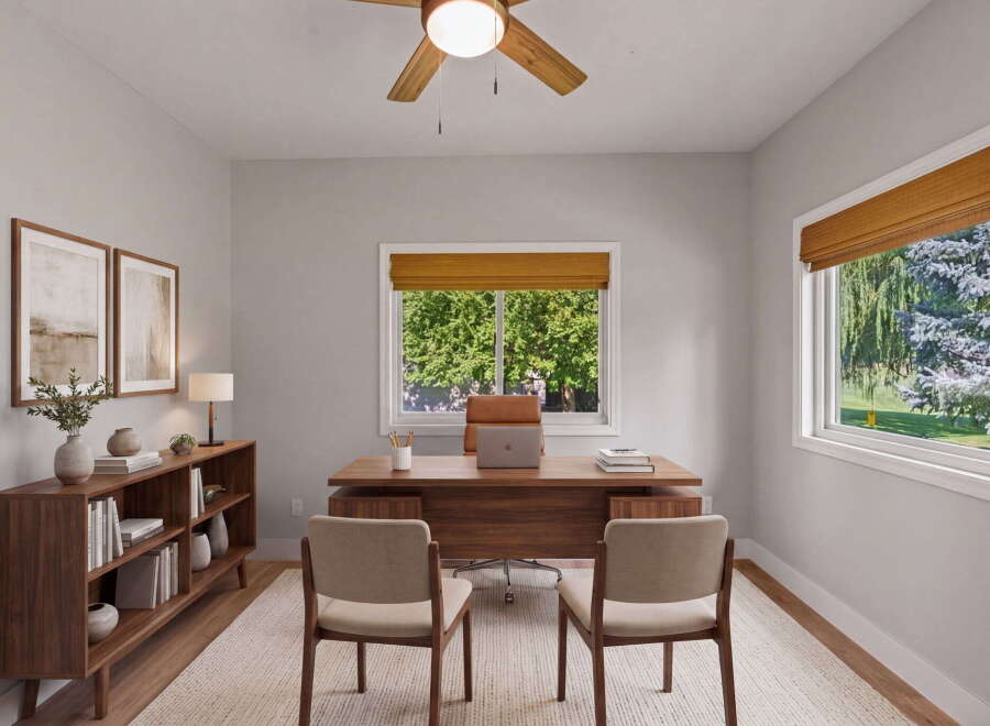 This home office features a spacious wooden desk with a laptop and two chairs, perfect for productivity.