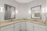 This elegant bathroom features a spacious double vanity with a light-colored countertop and two undermount sinks, perfect for busy mornings.