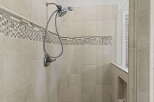 Experience luxury in this modern shower featuring elegant beige tiled walls accented with a decorative mosaic tile border.