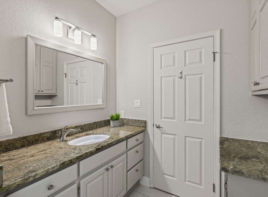 This bathroom features a spacious vanity with a granite countertop and a modern undermount sink, complemented by ample cabinet storage.