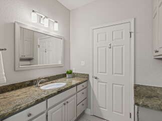 This bathroom features a spacious vanity with a granite countertop and a modern undermount sink, complemented by ample cabinet storage.