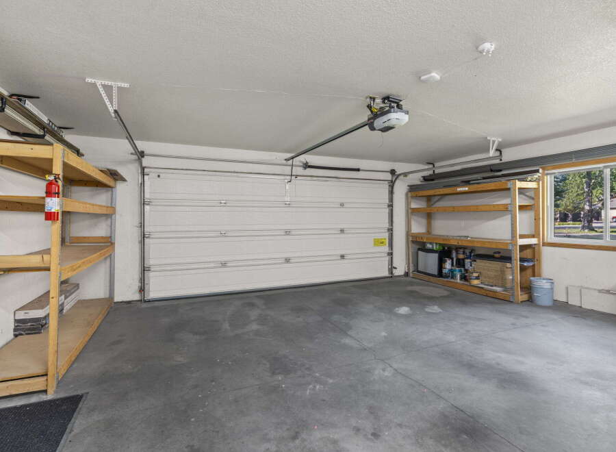 This spacious garage offers ample storage with multiple shelving units and a convenient overhead door.