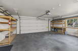 This spacious garage offers ample storage with multiple shelving units and a convenient overhead door.