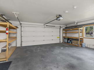 This spacious garage offers ample storage with multiple shelving units and a convenient overhead door.