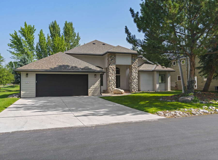 This stunning home features a modern exterior with stone accents and a spacious driveway leading to an attached garage.
