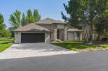This stunning home features a modern exterior with stone accents and a spacious driveway leading to an attached garage.