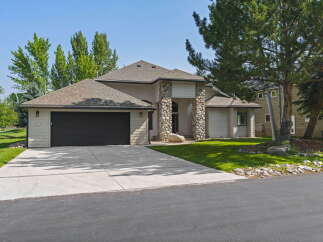 This stunning home features a modern exterior with stone accents and a spacious driveway leading to an attached garage.