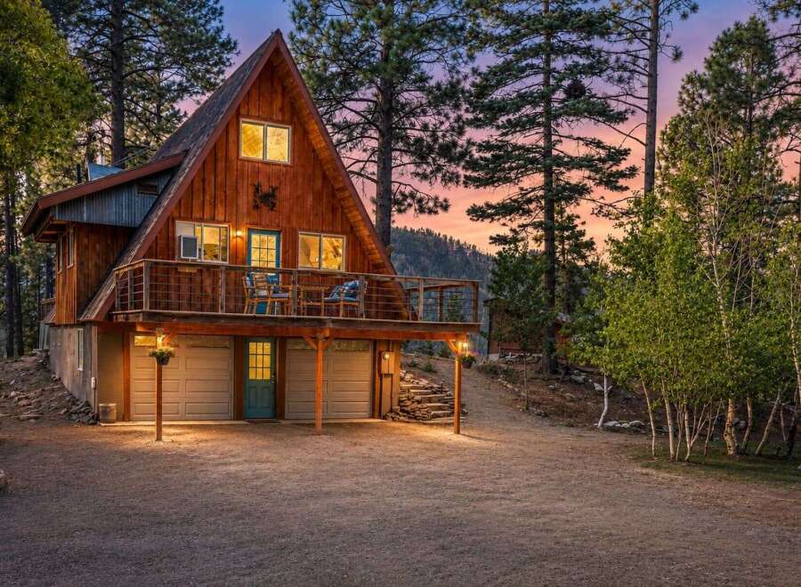 Experience the charm of this A-frame cabin nestled among tall pines, perfect for a mountain getaway.
