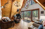 Experience rustic charm in this A-frame cabin living room, featuring a stunning antler chandelier and a cozy fireplace.