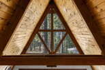 Experience the rustic charm of this A-frame cabin, featuring a unique triangular window that offers breathtaking views of the surrounding pine forest.