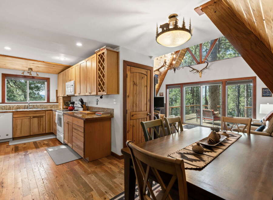 Experience rustic charm in this A-frame cabin, featuring a well-appointed kitchen with ample wooden cabinetry and a spacious dining area perfect for gatherings.
