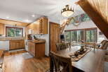 Experience rustic charm in this A-frame cabin, featuring a well-appointed kitchen with ample wooden cabinetry and a spacious dining area perfect for gatherings.