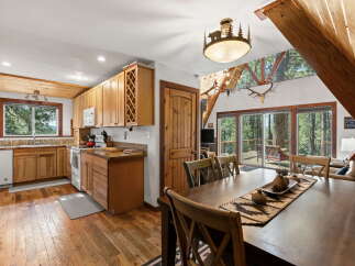Experience rustic charm in this A-frame cabin, featuring a well-appointed kitchen with ample wooden cabinetry and a spacious dining area perfect for gatherings.