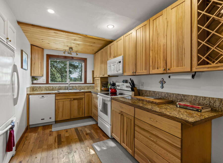 This charming kitchen boasts beautiful natural wood cabinetry and a sloped wood-paneled ceiling, creating a warm and inviting atmosphere.