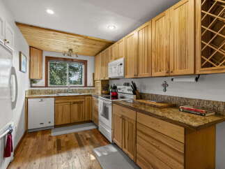 This charming kitchen boasts beautiful natural wood cabinetry and a sloped wood-paneled ceiling, creating a warm and inviting atmosphere.