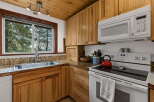 Experience rustic charm in this cozy cabin kitchen, featuring warm wood cabinetry and a stunning view through the large window.