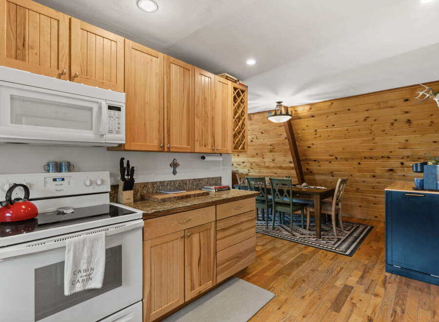 This charming kitchen features warm, natural wood cabinetry and a sleek white microwave.