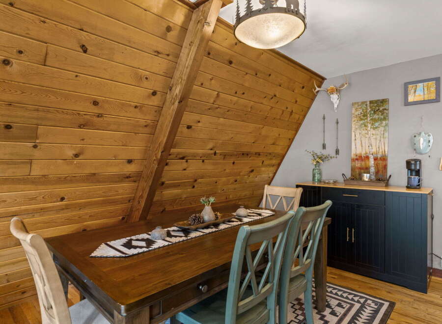 Experience rustic charm in this dining area, featuring a warm wooden table adorned with a decorative runner and pinecones.