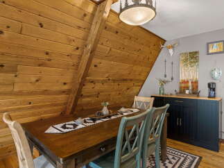 Experience rustic charm in this dining area, featuring a warm wooden table adorned with a decorative runner and pinecones.