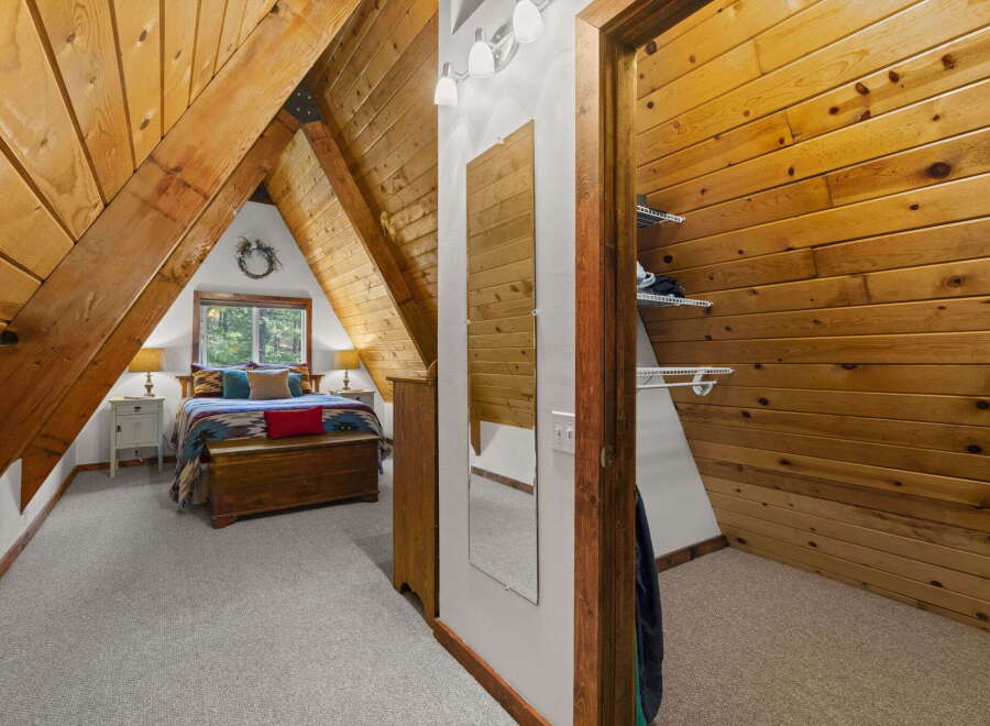 Discover this charming A-frame bedroom, featuring a cozy bed adorned with a colorful Southwestern-inspired blanket and plush pillows.