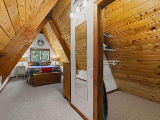 Discover this charming A-frame bedroom, featuring a cozy bed adorned with a colorful Southwestern-inspired blanket and plush pillows.