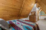 Experience rustic charm in this A-frame bedroom, featuring a cozy bed adorned with a vibrant Native American-inspired blanket.