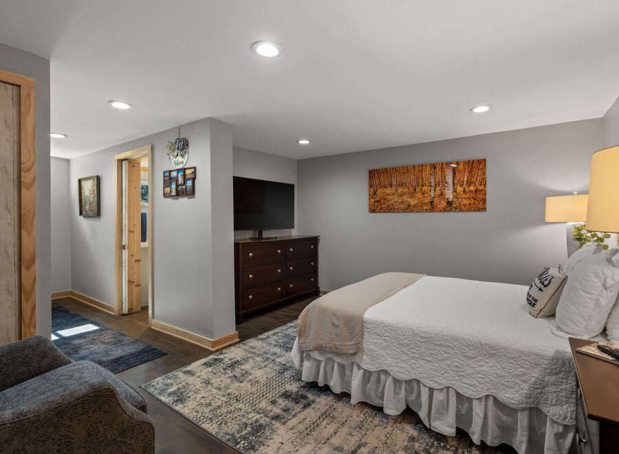 This inviting bedroom features a comfortable queen-size bed adorned with crisp white linens and a cozy throw blanket.