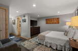 This inviting bedroom features a comfortable queen-size bed adorned with crisp white linens and a cozy throw blanket.