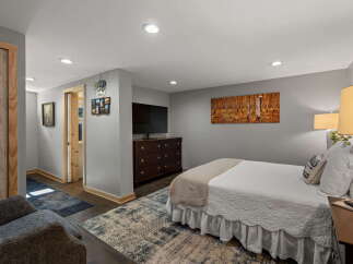 This inviting bedroom features a comfortable queen-size bed adorned with crisp white linens and a cozy throw blanket.