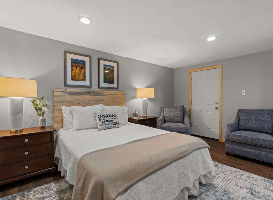 Experience cozy comfort in this charming bedroom, featuring a rustic wooden headboard and plush bedding.