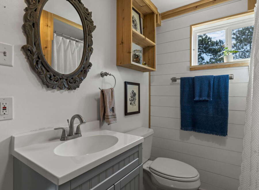 This charming bathroom features a stylish vanity with a white countertop and a gray cabinet base, complemented by a large ornate mirror.