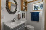 This charming bathroom features a stylish vanity with a white countertop and a gray cabinet base, complemented by a large ornate mirror.