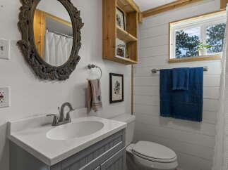 This charming bathroom features a stylish vanity with a white countertop and a gray cabinet base, complemented by a large ornate mirror.