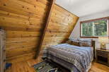 Cozy A-frame bedroom featuring warm wood paneling and a comfortable queen-size bed adorned with rustic bedding.