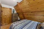 Experience rustic charm in this cozy bedroom featuring a wooden plank accent wall and a comfortable bed with a nature-themed comforter.