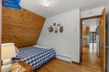 Discover cozy living in this charming bedroom featuring a unique wood-paneled A-frame wall and a classic blue and white checkered bedspread.