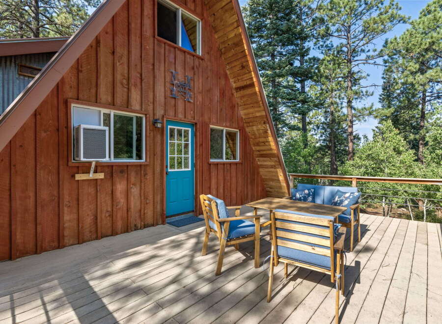 Enjoy the serene mountain setting from the spacious wooden deck of this charming A-frame cabin.