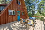 Enjoy the serene mountain setting from the spacious wooden deck of this charming A-frame cabin.