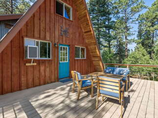 Enjoy the serene mountain setting from the spacious wooden deck of this charming A-frame cabin.
